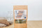 Bag of MagicT Pure Chamomile on a wooden surface with chamomile flowers spilling out.