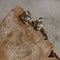 Gold earrings with clear gemstones on a textured stone surface
