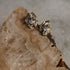 Gold earrings with clear gemstones on a textured stone surface