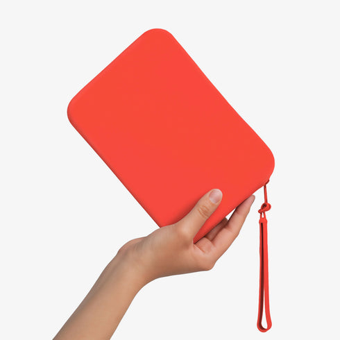 The Strapsicle Clutch in Neon Flame, Regular size, held in one hand