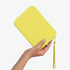 The Strapsicle Clutch in Neon Lemon, Regular size, held in one hand