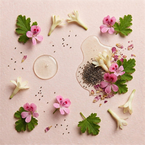 Flat lay of the ingredients behind the day cream: rose geranium and tuberose flowers, chia seeds and a dish of cream