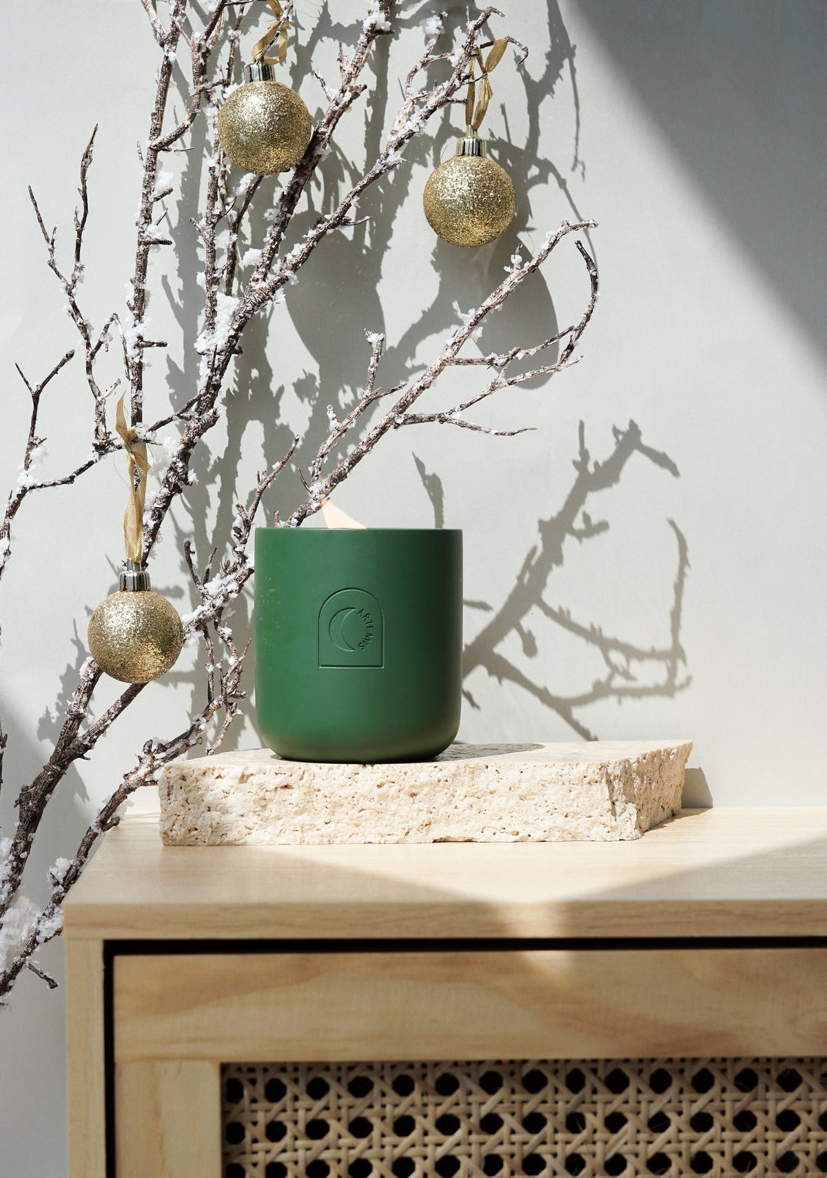 Artemis Under The Mistletoe candle styled with gold baubles and bare branches