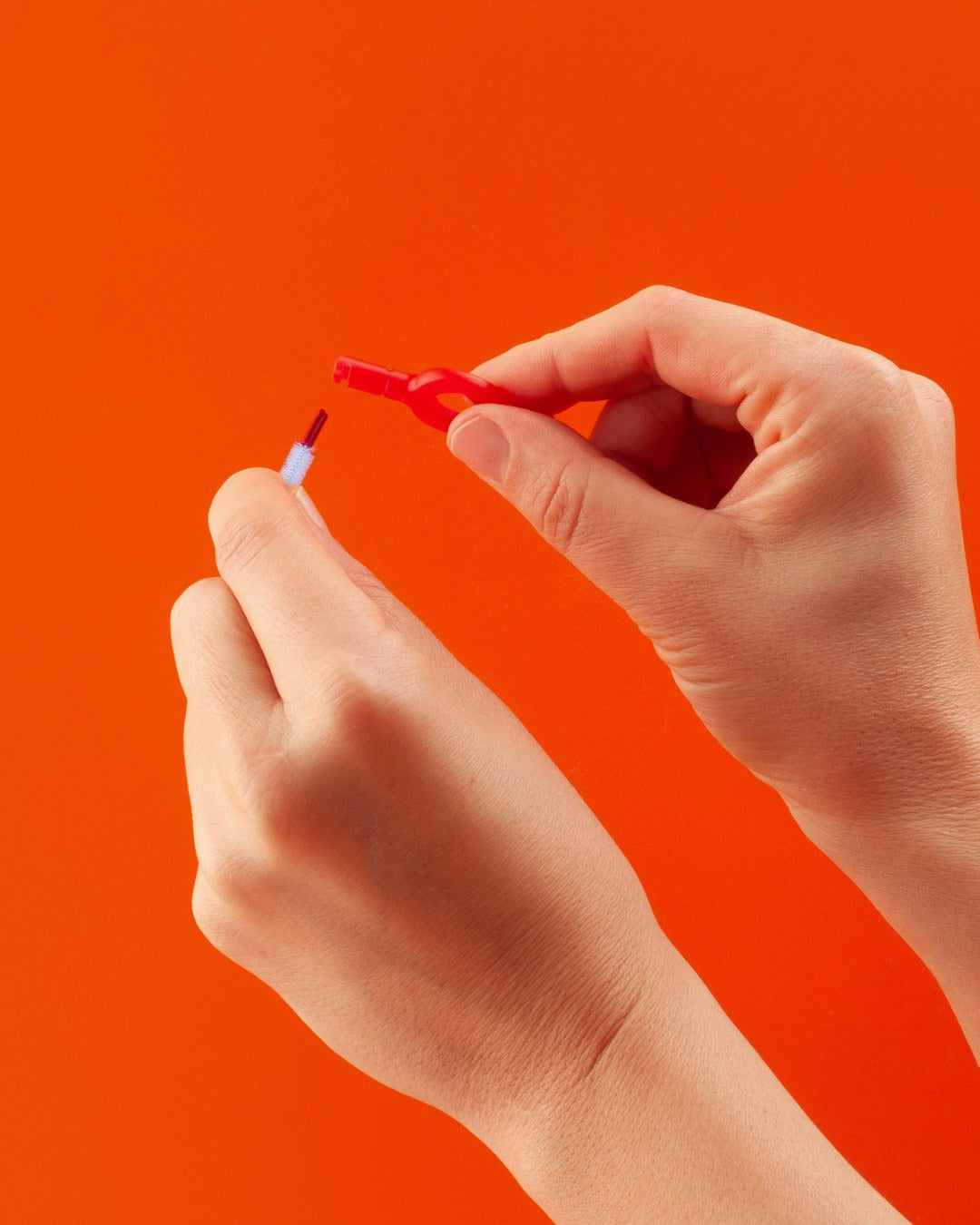 A Curaprox CPS 405 perio brush held against a red background