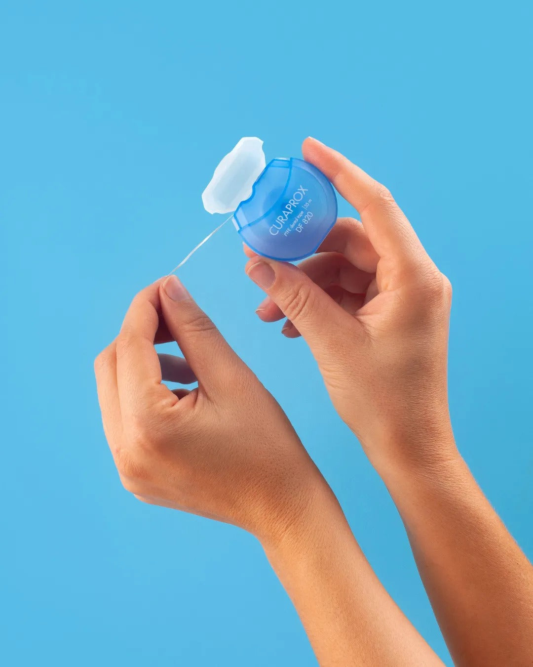 Curaprox DF 820 dental tape being pulled from the dispenser