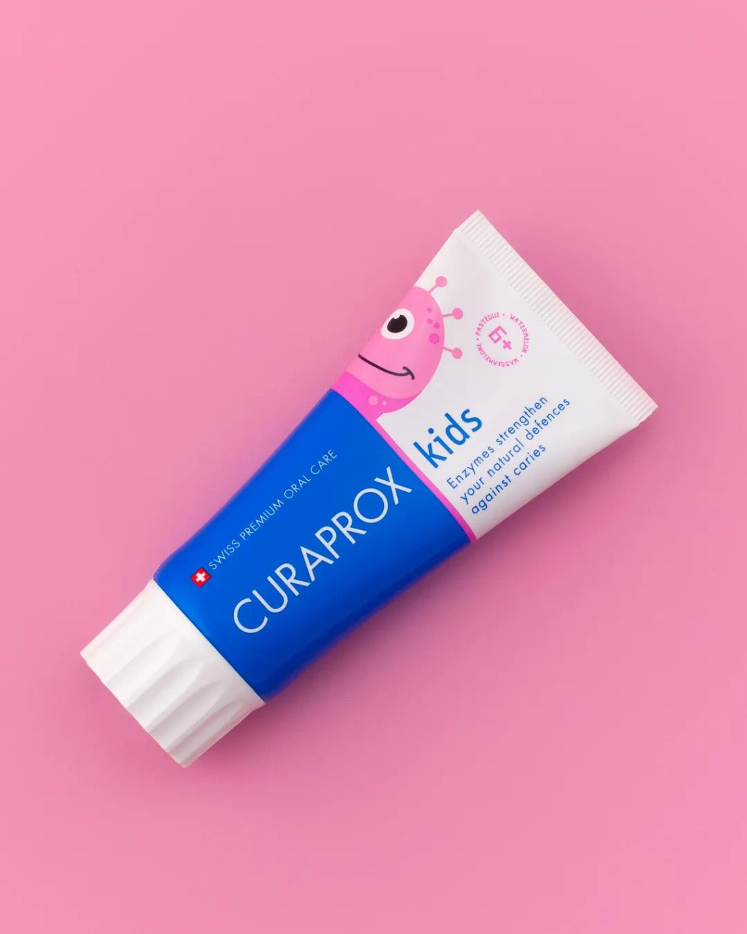 Curaprox Kids watermelon toothpaste tube on a pink background