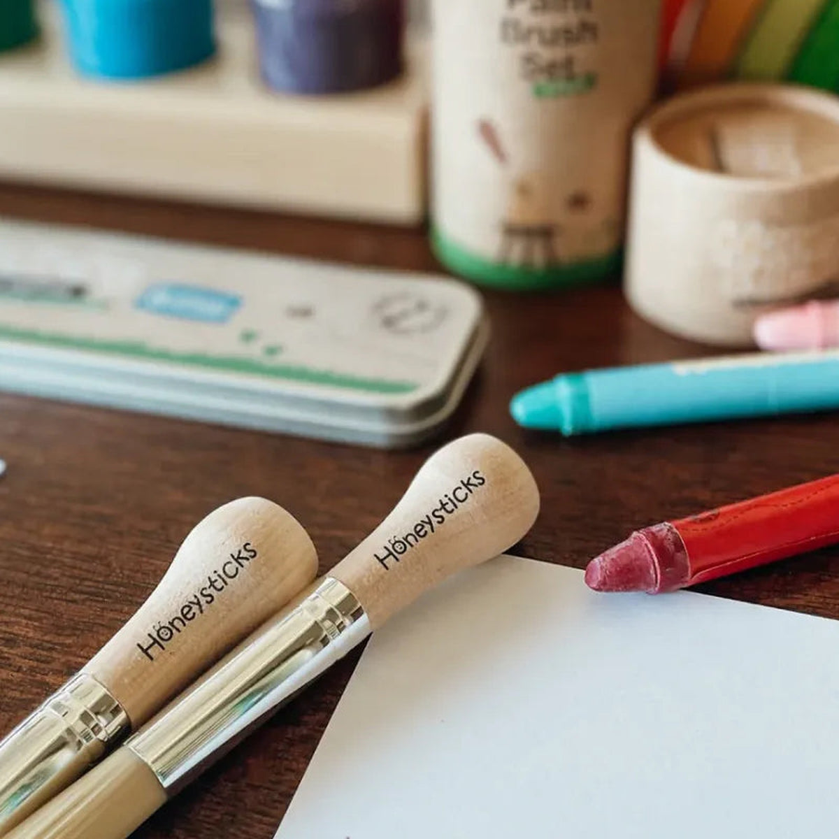 The My First paintbrushes on a table beside paper and crayons