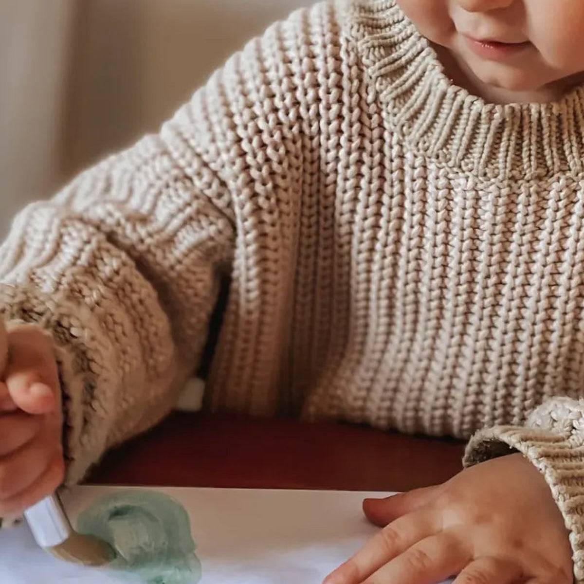 A toddler holding a My First paintbrush in a whole-hand grip