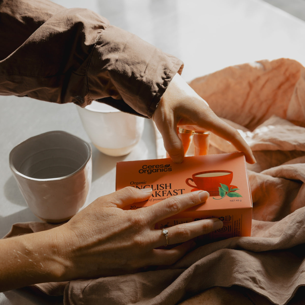 Hands opening a box of Ceres Organics English Breakfast Tea