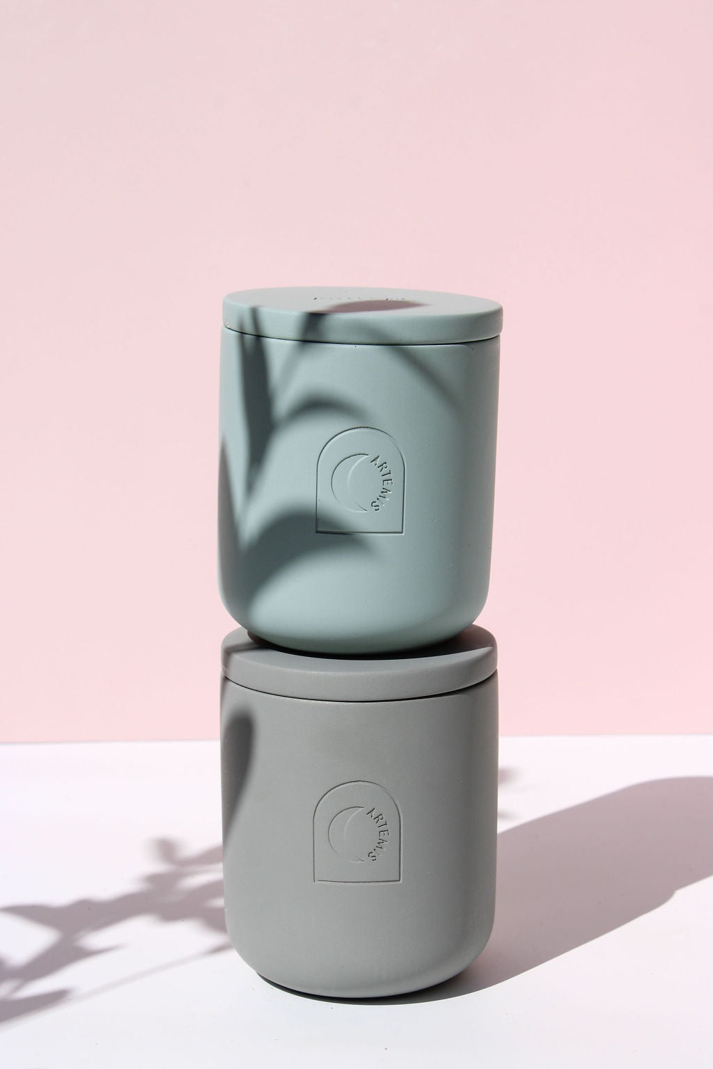 Two Artemis Longitude candles stacked, showing the lid and the moon emblem