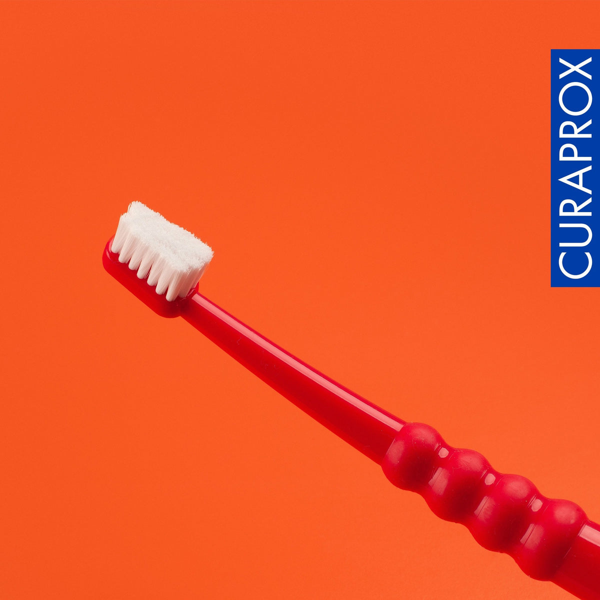 Curaprox CS surgical toothbrush on a red background
