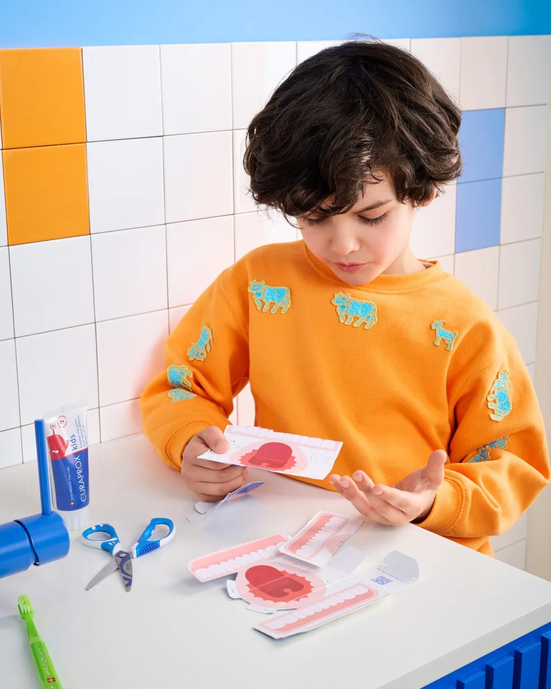 A child brushing at the basin with Curaprox Kids toothpaste
