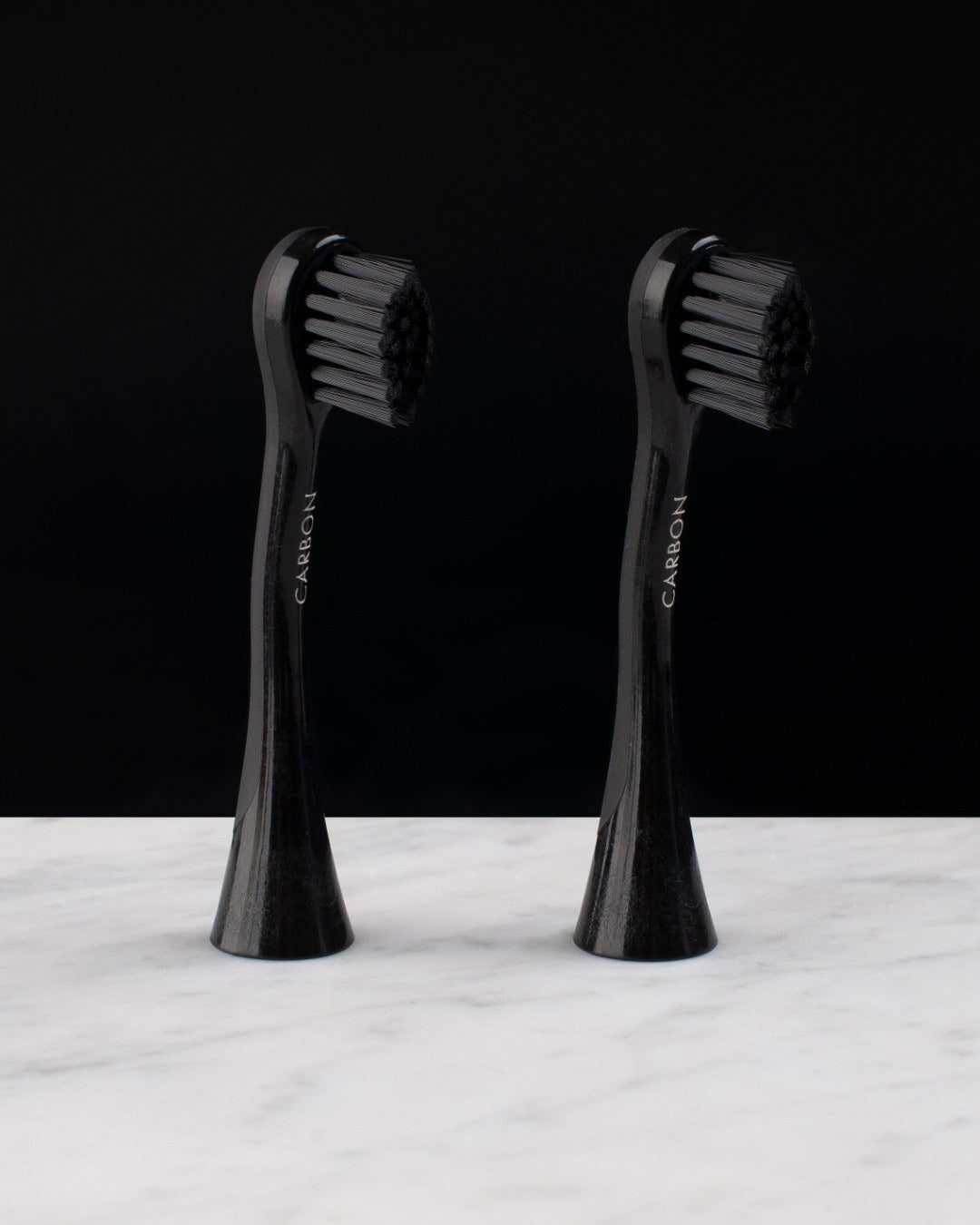 Two Curaprox Black is white carbon brush heads standing upright
