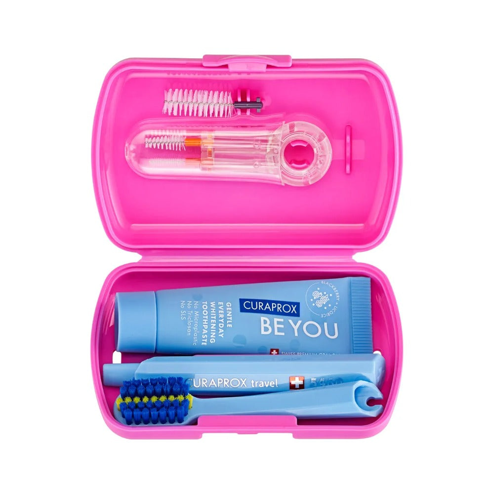 Curaprox ortho travel set in pink, open to show the toothbrush, toothpaste and interdental brushes