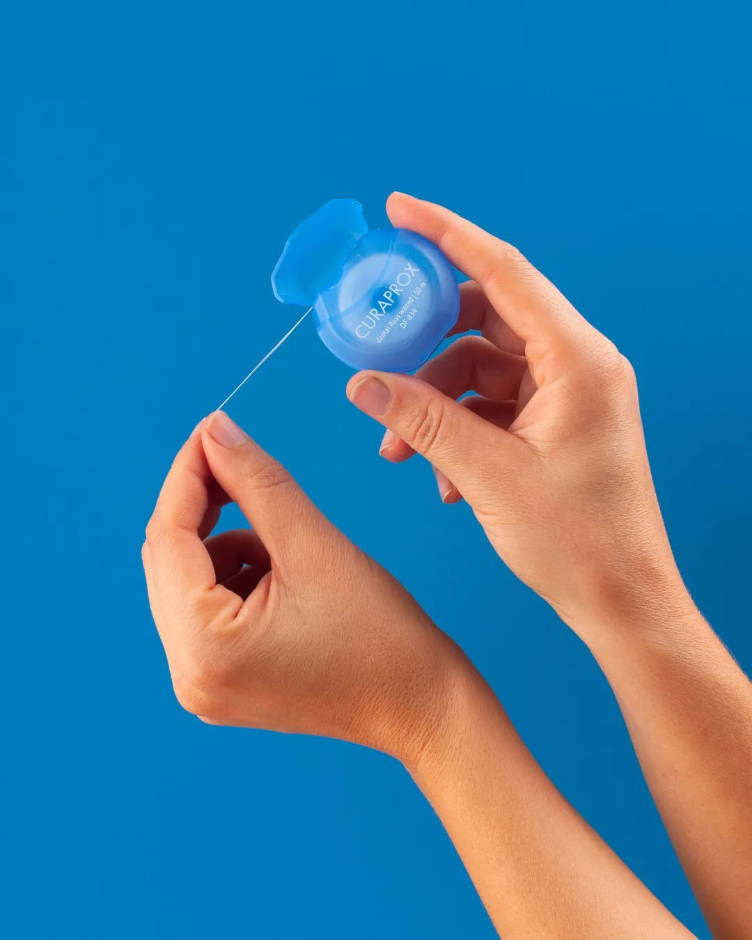 Curaprox DF 834 dental floss being pulled from the dispenser