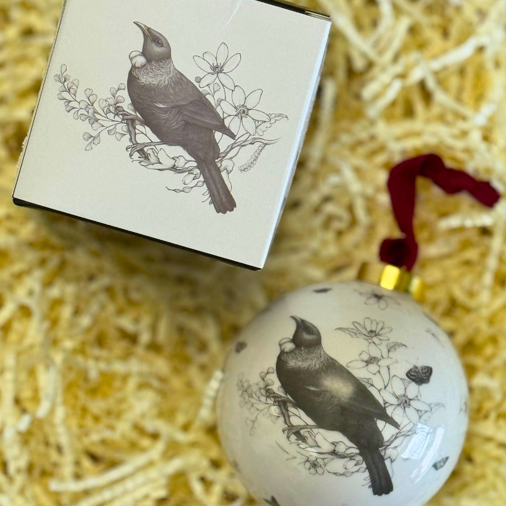 The Home is Here tui bauble beside its black gift box