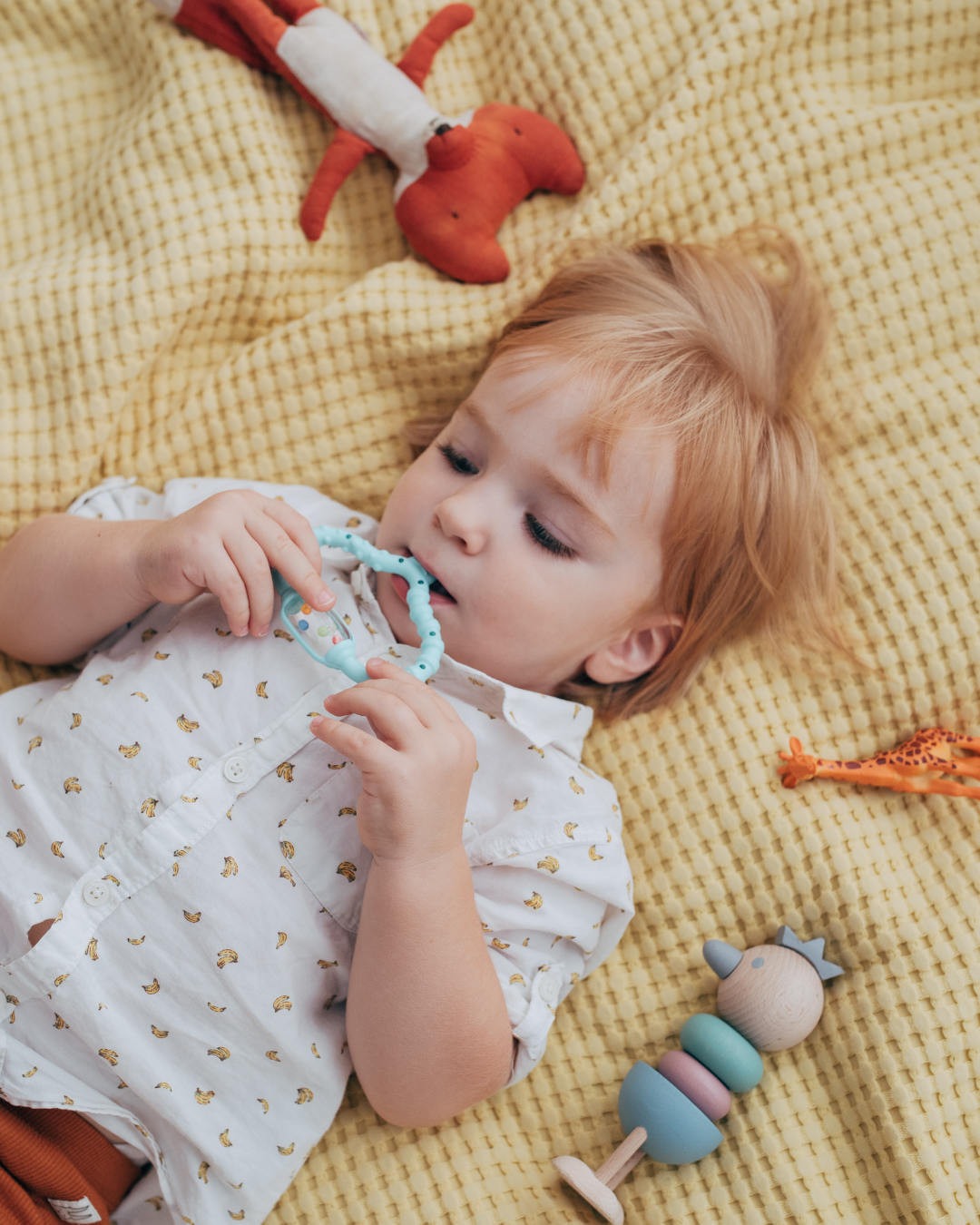 A baby holding the Curaprox teething ring