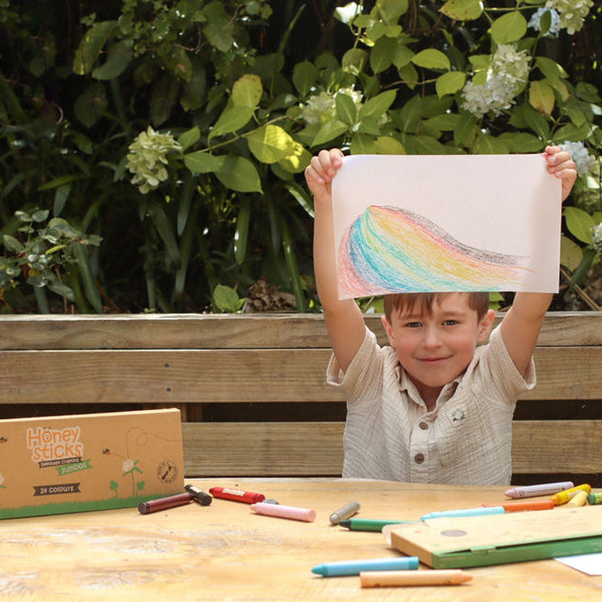 A child holding up a rainbow drawing made with the jumbo crayons
