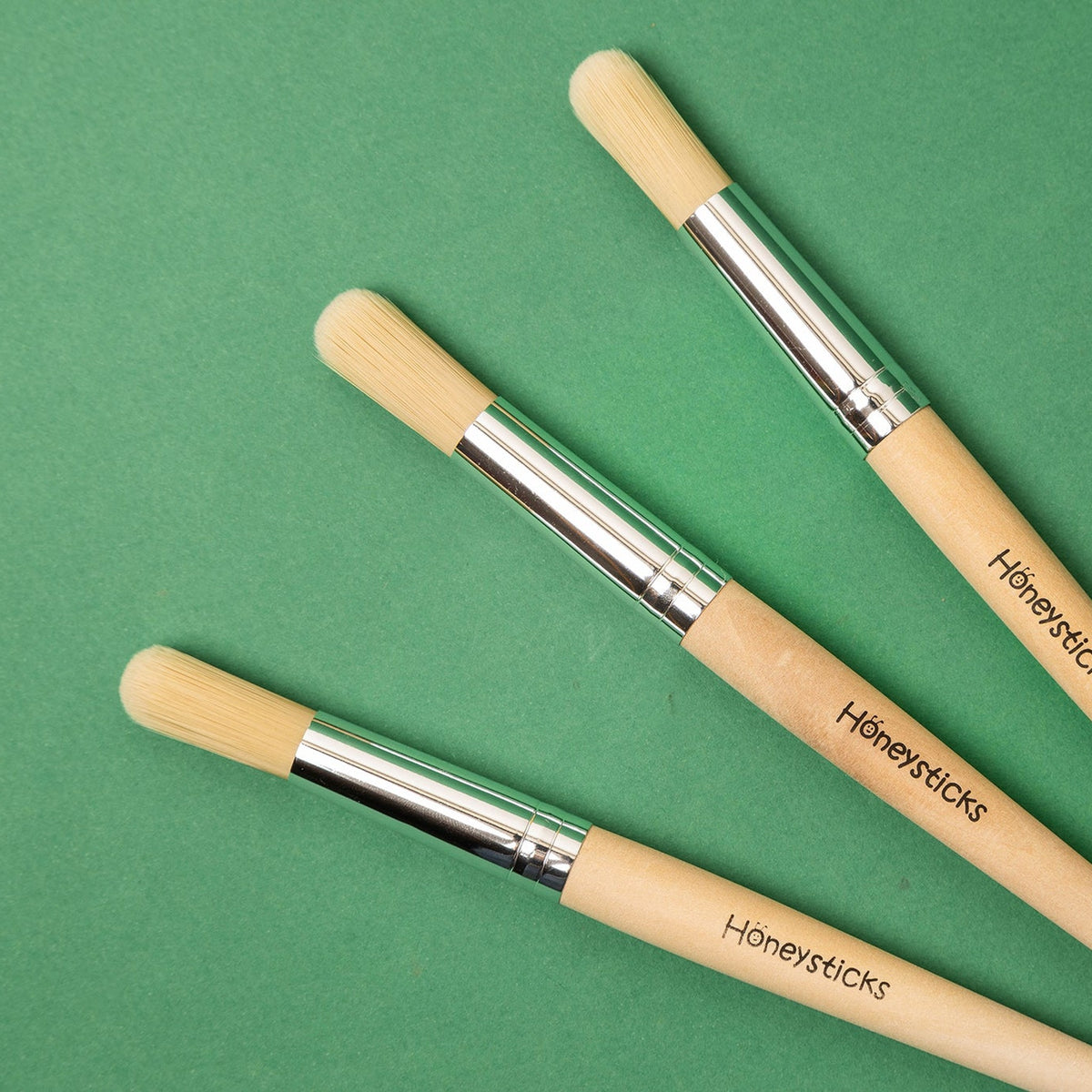 The three jumbo paintbrushes laid out on a green background