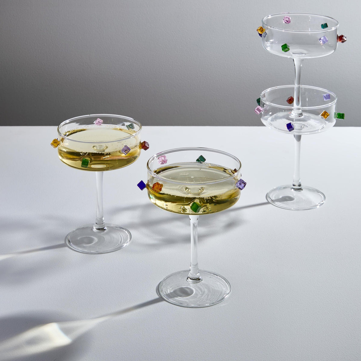 Fazeek Jewel Coupes filled with a pale cocktail, stacked and lit to show the glass cubes