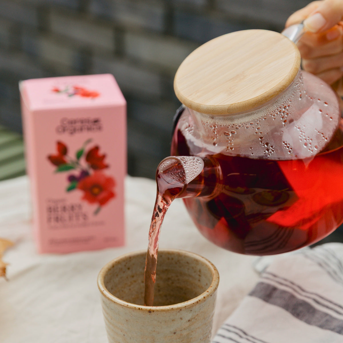 Berry Fruits Herbal Tea poured from a glass teapot