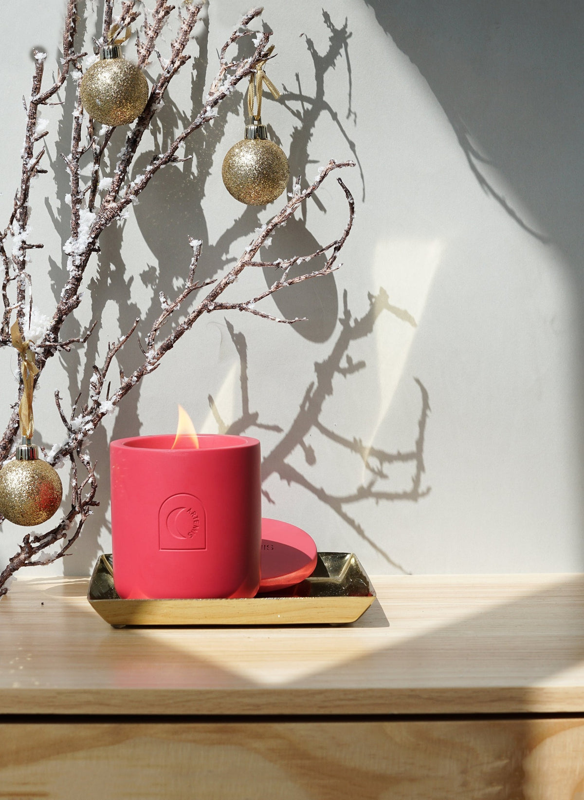 Festive Delight candle lit on a gold tray with gold baubles behind