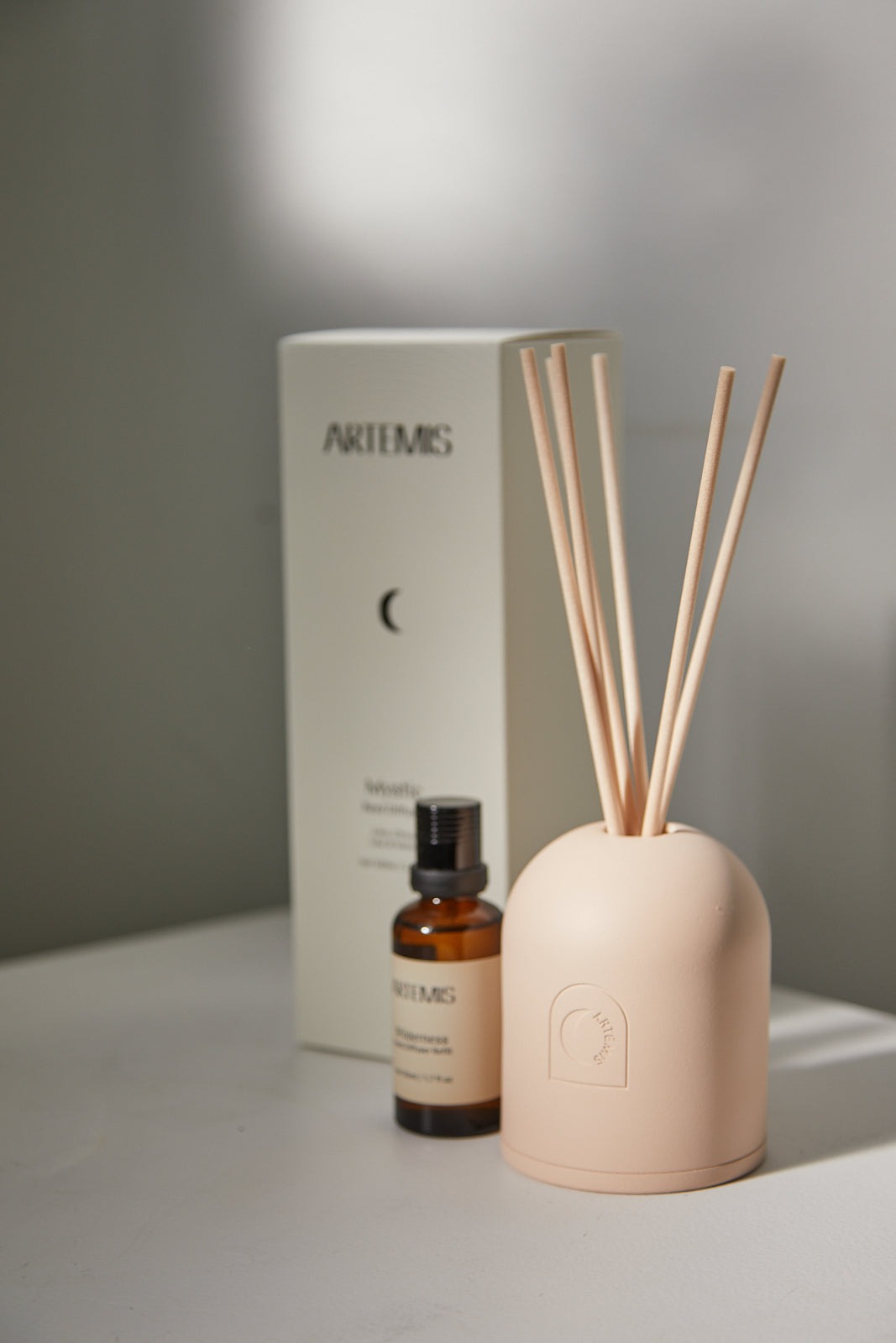 Artemis Wilderness reed diffuser in a pale pink vessel with its box and refill oil