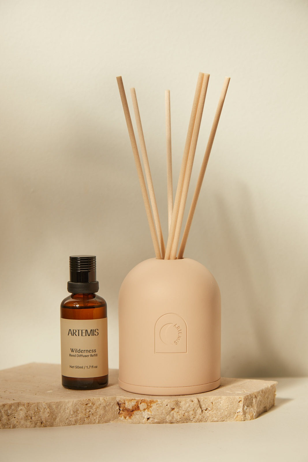The Wilderness reed diffuser with six reeds, styled on a wooden block