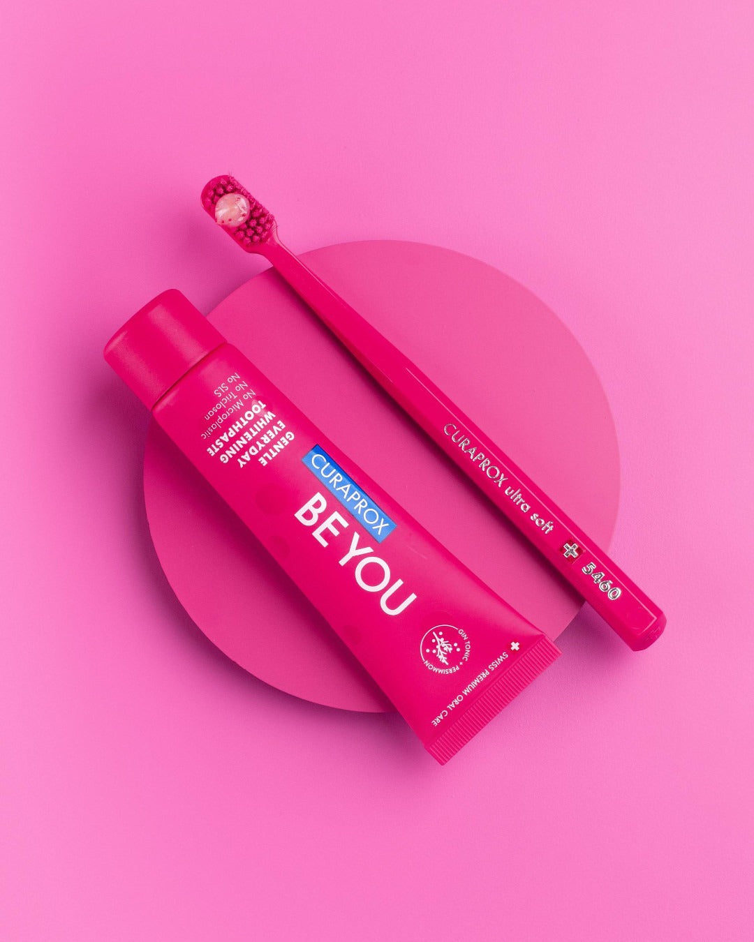 Curaprox Be you Gin Tonic and Persimmon tube and carton on a pink background