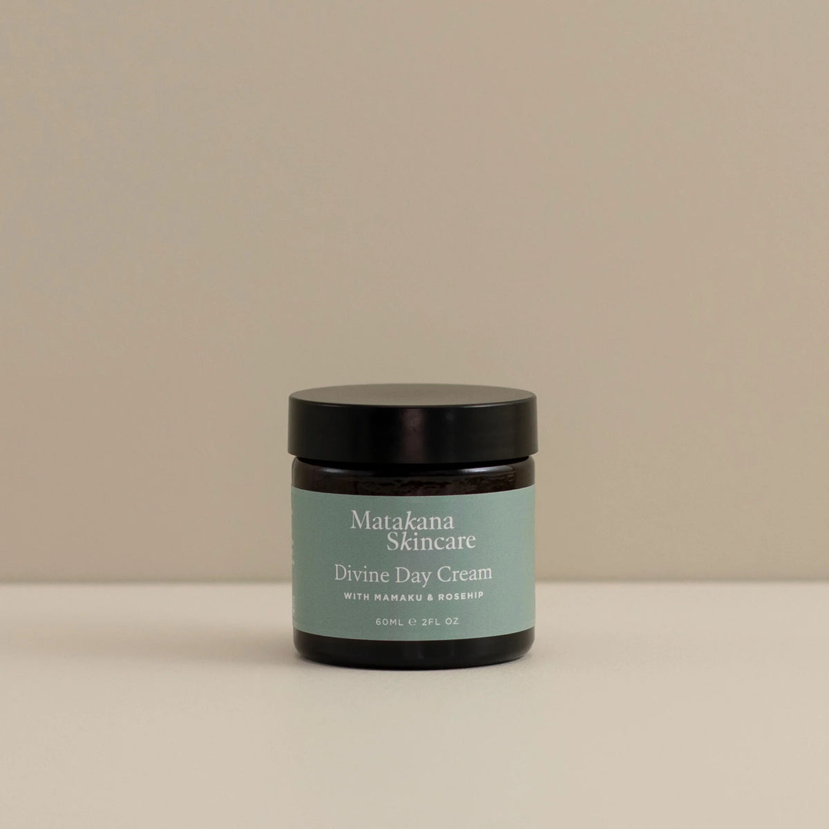 A jar of Divine Day Cream by Matakana Skincare sits on a benchtop. The jar is glass with a green label.