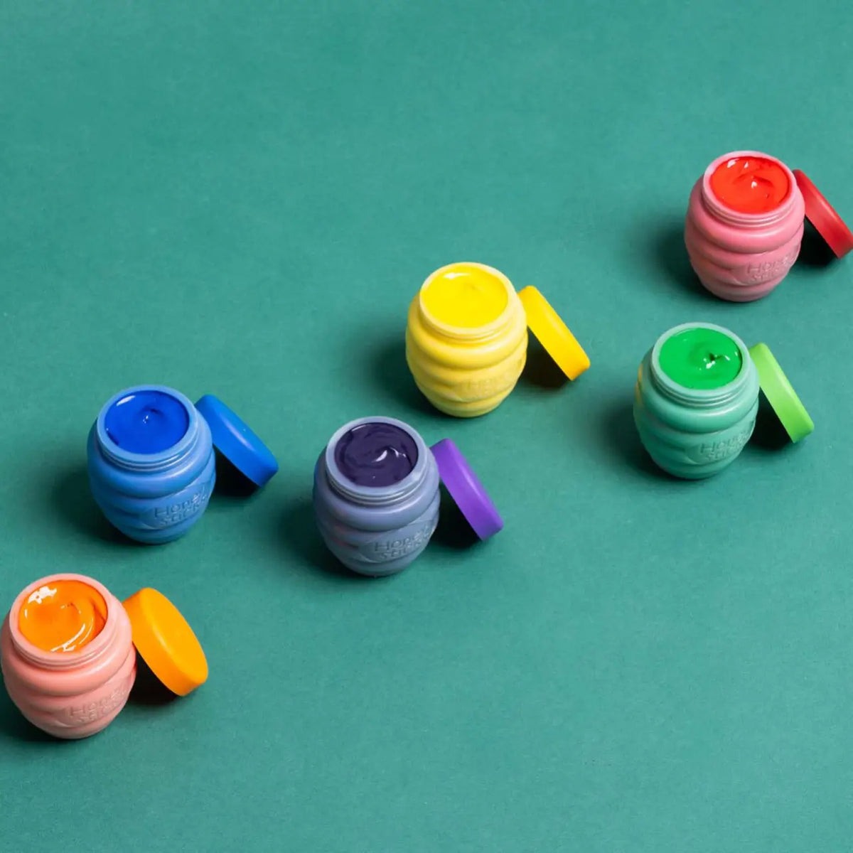 The six finger paint pots open on a teal background