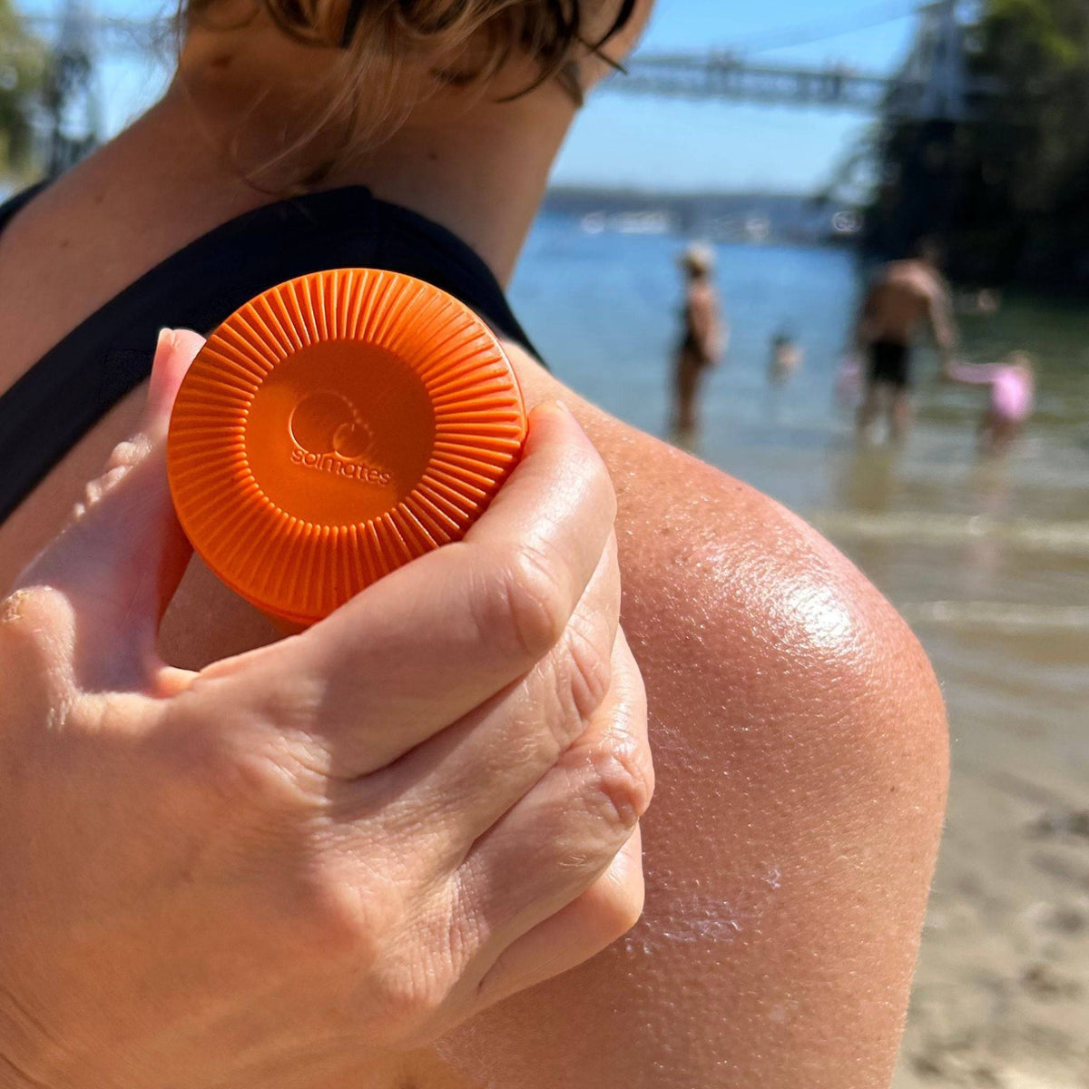 A Solmates applicator being rolled onto a shoulder at the beach