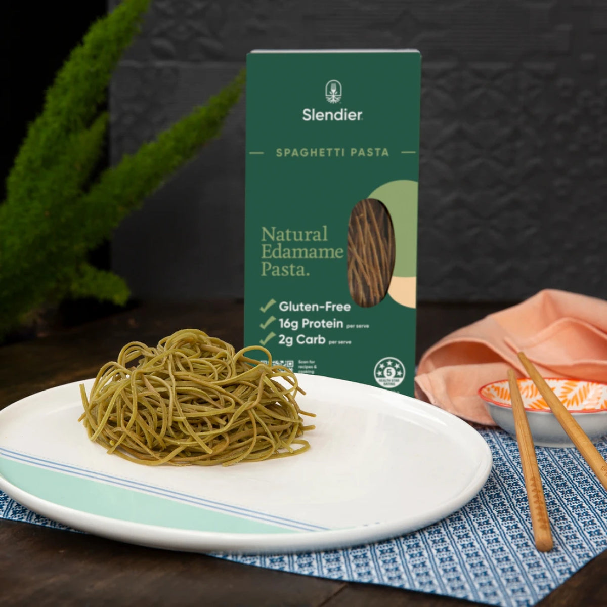 Cooked edamame bean spaghetti served on a plate beside the Slendier box