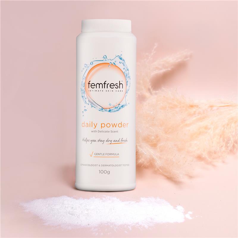 Femfresh Daily Powder bottle standing on pink with a scatter of powder