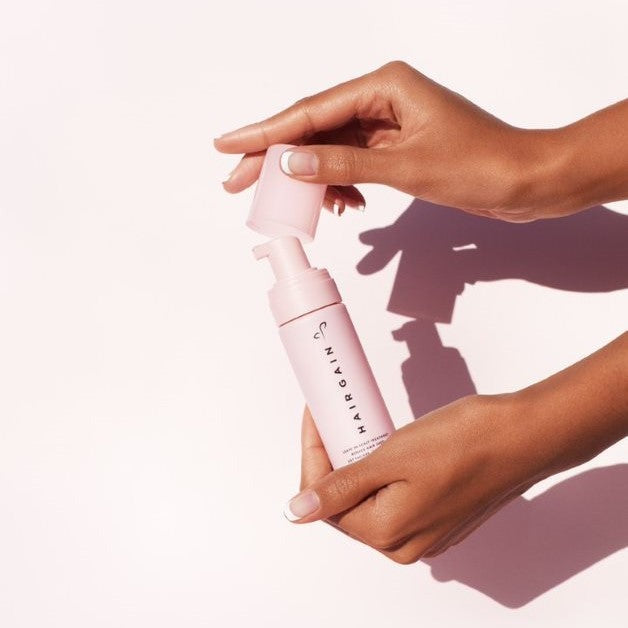 Hands pumping Hair Gain Scalp Foam from the bottle