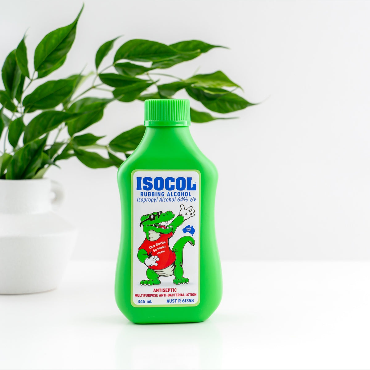 Isocol Rubbing Alcohol Antiseptic Lotion 345ml bottle on white beside a plant