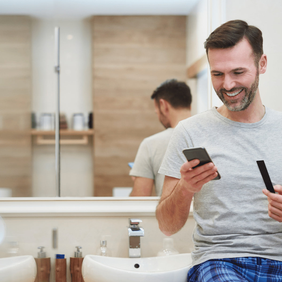 A man in a bathroom scanning a Vivoo urine test strip with the app on his phone